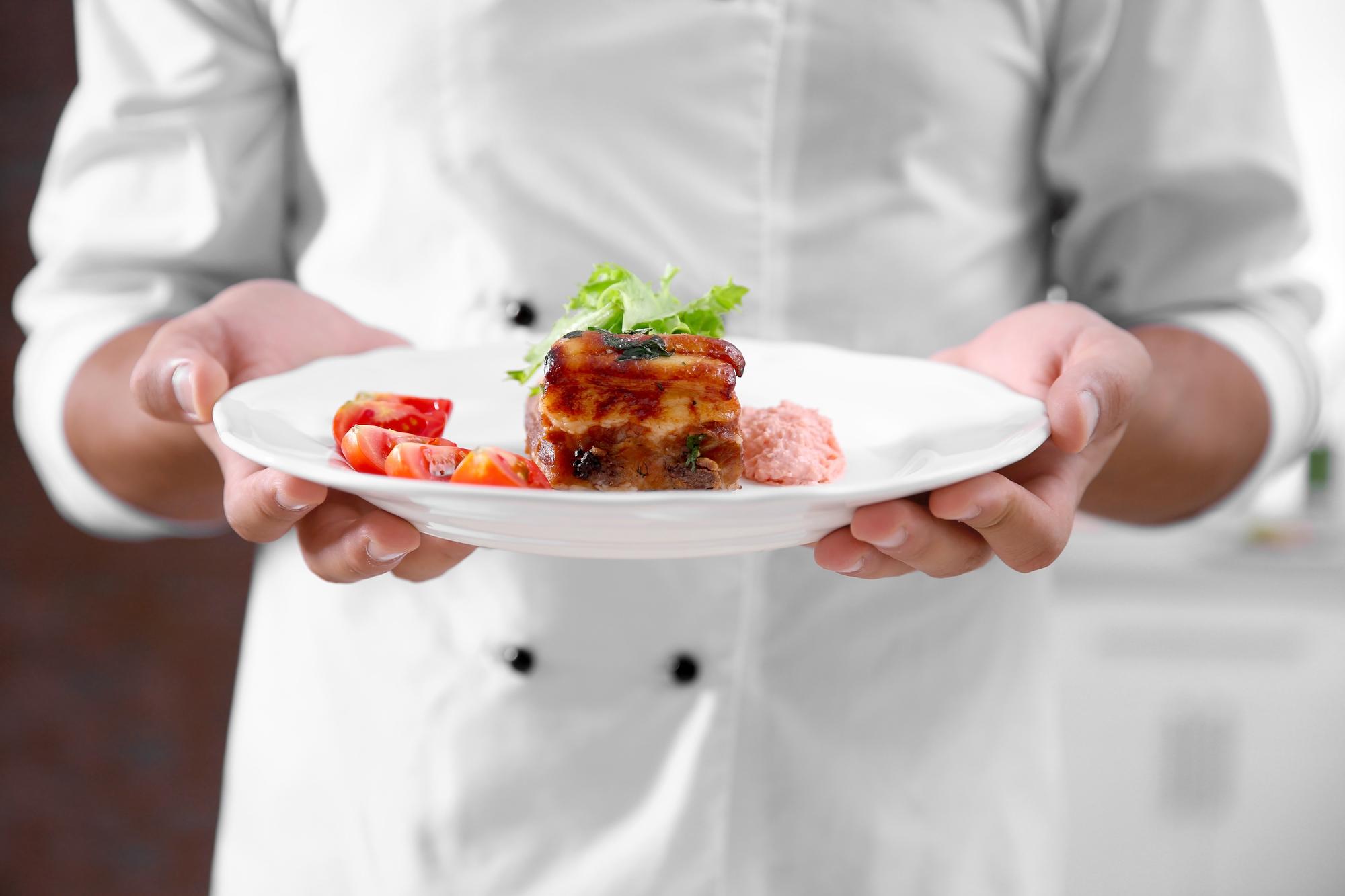 Hands plating a premium dish on wooden table